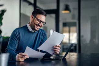 Smiling businessman, holding and reading one contract