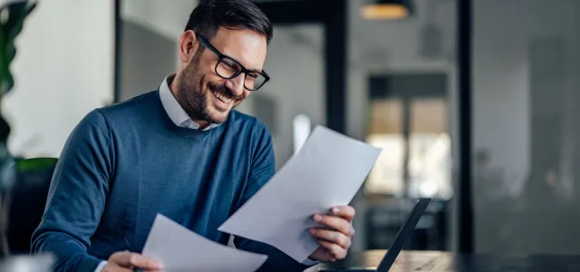 Smiling businessman, holding and reading one contract